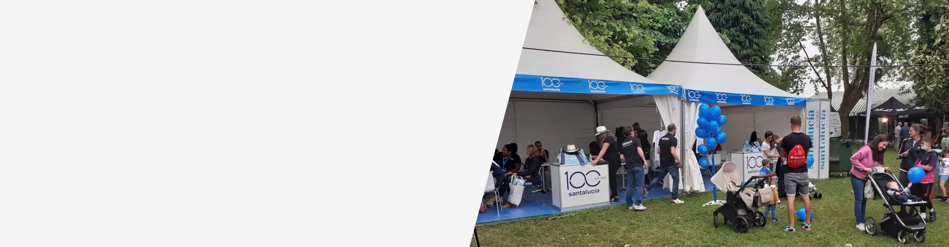 Stand de Santalucía en un evento al aire libre con carpas corporativas, material promocional y asistentes participando en actividades familiares