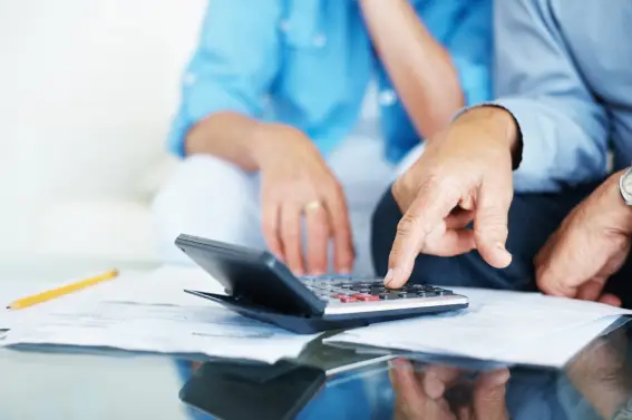 Personas revisando facturas y calculando gastos con una calculadora sobre una mesa.