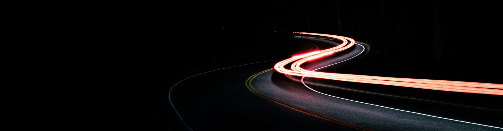 Luz de estelas rojas y blancas de coches en carretera curva durante la noche