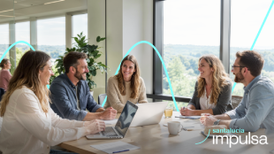 Equipo de trabajo colaborando en una reunión en oficina con ordenadores portátiles, programa Santalucía Impulsa