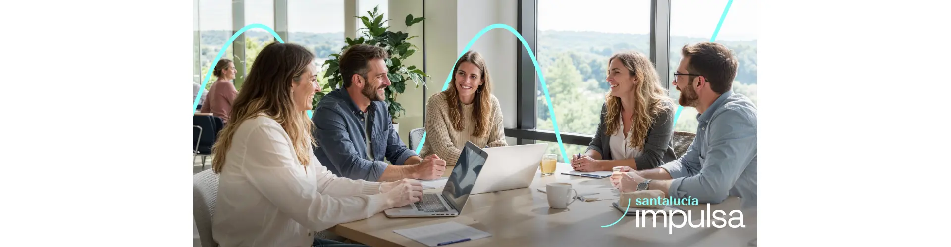 Reunión de trabajo en oficina con ordenadores y documentos, iniciativa Santalucía Impulsa para innovación y emprendimiento.
