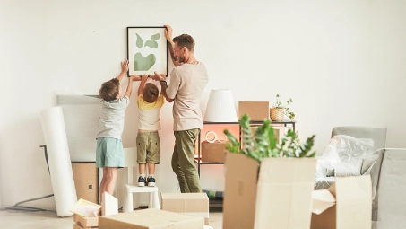 Colocación de cuadro en pared durante mudanza, concepto de protección del hogar y seguros de vivienda