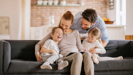 Familia reunida en el sofá en casa, soluciones Santalucía Seguros para familias