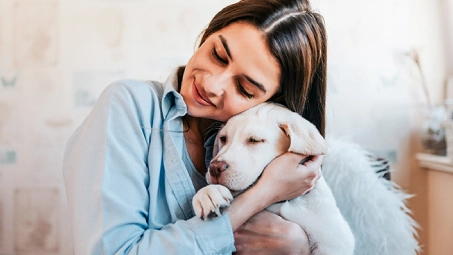Persona abrazando a un perro en casa, soluciones Santalucía para mascotas