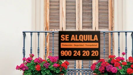 Balcón con macetas de flores y cartel negro con letras naranjas que dice 