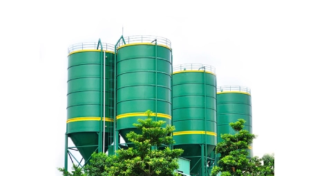 Conjunto de silos industriales verdes rodeados de árboles, utilizados para almacenamiento