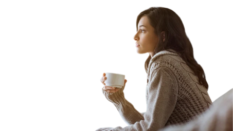 Persona sentada sosteniendo una taza blanca con ambas manos, vistiendo suéter de punto