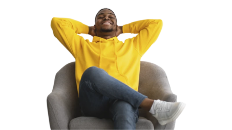 Persona sentada en sillón con sudadera amarilla y piernas cruzadas, manos detrás de la cabeza