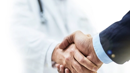 Apretón de manos entre médico y empresario, acuerdo en servicios de salud para empresas y colaboración profesional