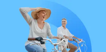 Dos personas montando en bicicleta sobre un fondo azul, una de ellas con sombrero y gesto dinámico mientras avanzan