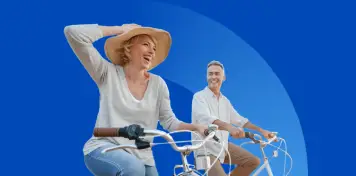 Dos personas montando en bicicleta sobre un fondo azul, una de ellas con sombrero y gesto dinámico mientras avanzan