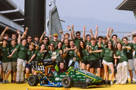 Equipo de estudiantes junto a un monoplaza de competición en el paddock de un circuito durante una prueba del programa Formula Student.